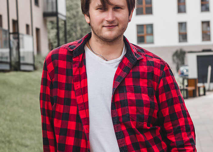 Young man wearing a red plaid shirt outdoors, representing reflections on dumbest fad participated in discussions.