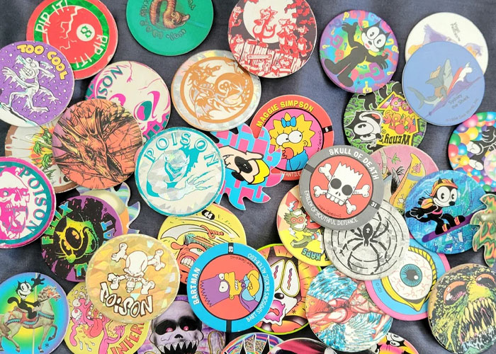Colorful collection of vintage pogs and slap bracelets, representing popular fads many participated in during childhood.