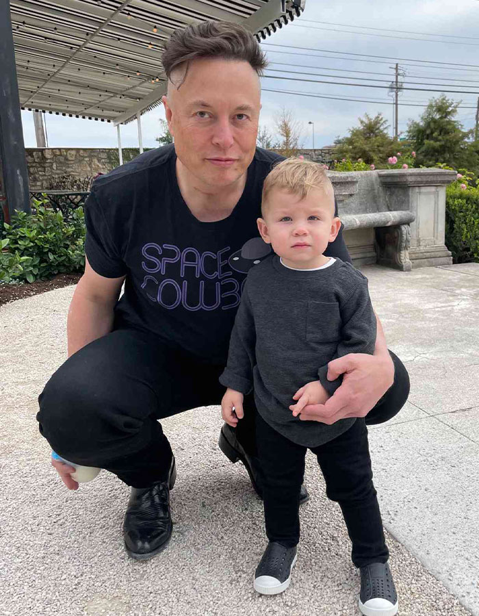 Elon Musk crouching outdoors with young child, raising concerns after glitching and visible black eye at White House event