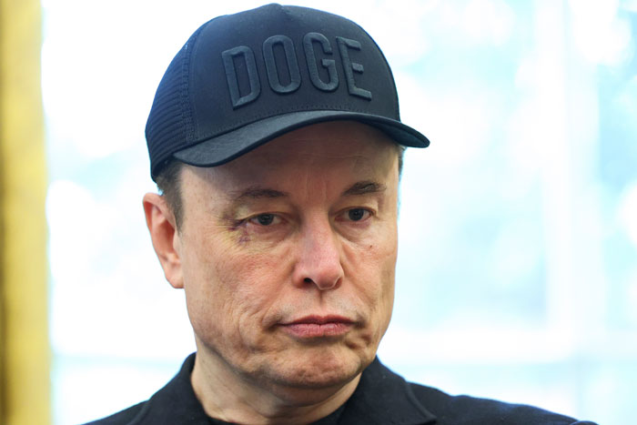 Elon Musk wearing a DOGE cap with a noticeable black eye, raising concerns after glitching and head ticks at the White House.
