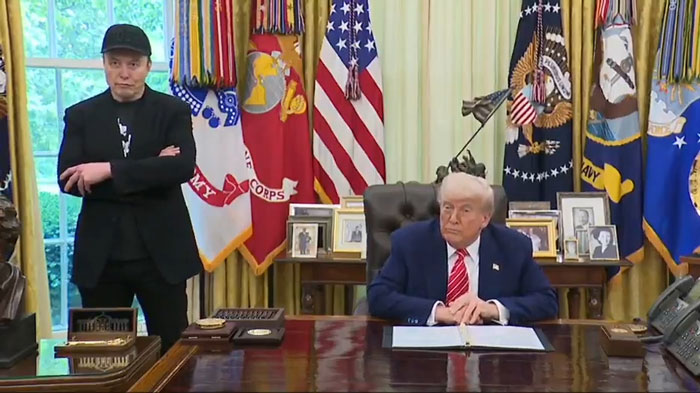Elon Musk with black eye and head ticks standing near former President Trump in the White House Oval Office.