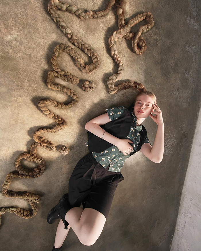 Vivian Musk modeling debut lying on floor with long braided hair arranged around, showcasing unique fashion style.