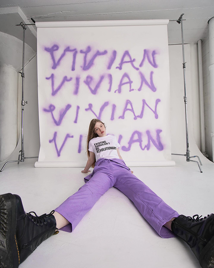 Vivian Musk posing for modeling debut against a backdrop with her name in purple graffiti-style letters.