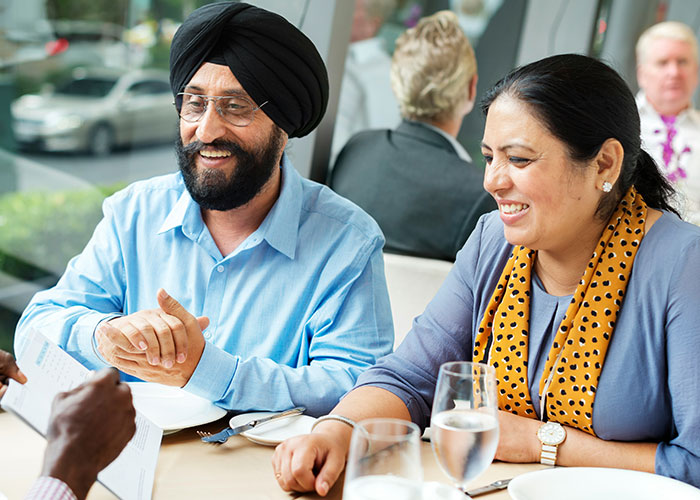 Smiling parents having a conversation at a restaurant, reflecting on the worst things their kids did in public.