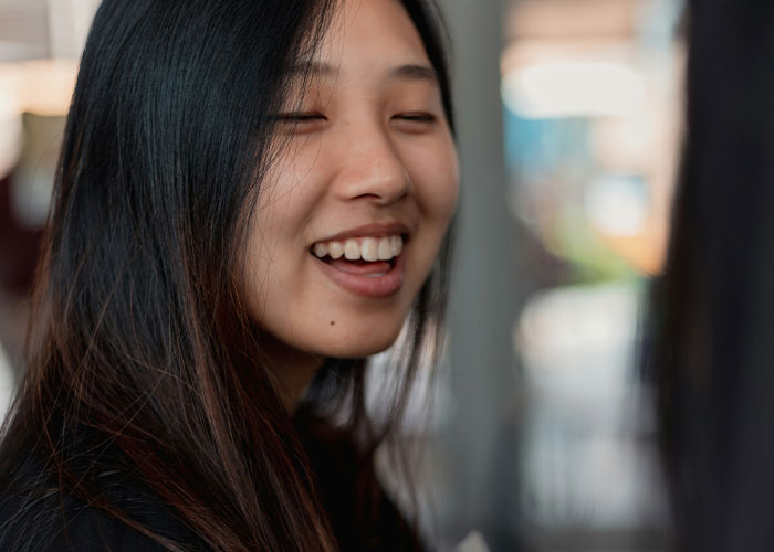 Smiling woman with long black hair reacting to stories about the worst things kids did in public shared by parents.