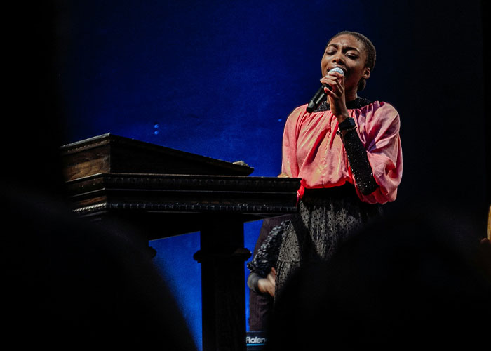 Woman singing passionately into a microphone on stage, illustrating parents' worst kids public moments that made them want to disappear.