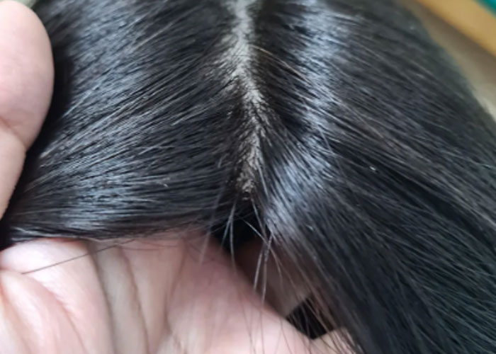 Close-up of a hand holding black hair showing scalp and strands, illustrating messy hair kids did in public parents shared