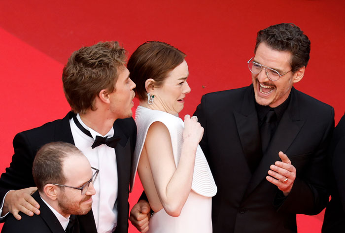 Emma Stone reacting with laughter alongside actors on the red carpet at Cannes film festival event.