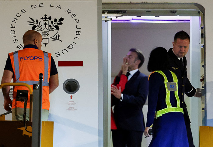 French President Emmanuel Macron and wife seen near airplane door after shoving incident, lip reader reveals conversation details.