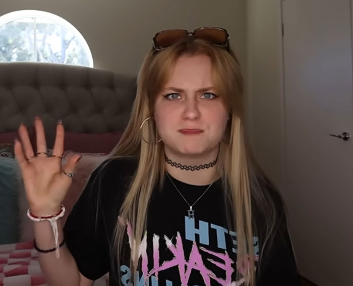 Young woman expressing concern while discussing companies using AI to conduct job interviews in a casual indoor setting.