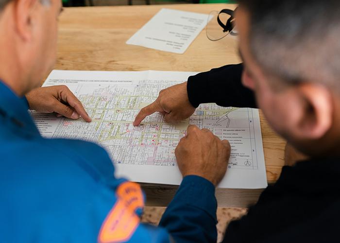 Two men closely examining a detailed map, focusing on planning and problem-solving in an engineering context.