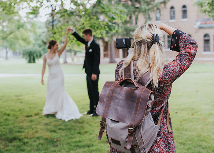 Photographer capturing a bride and groom dancing outdoors, highlighting a woman's wedding revenge controversy.