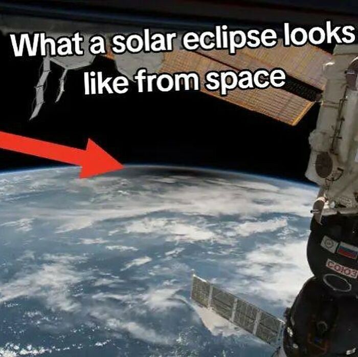 View of a solar eclipse from space showing Earth’s atmosphere and parts of a spacecraft orbiting the planet.