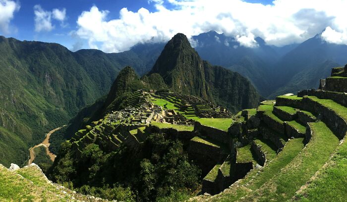 A panoramic view of Machu Picchu ancient ruins surrounded by green mountains, showcasing one of the world's must-see wonders.