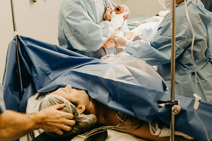 Medical team delivering newborn baby during birth, highlighting gruesome facts about pregnancy and birth experiences
