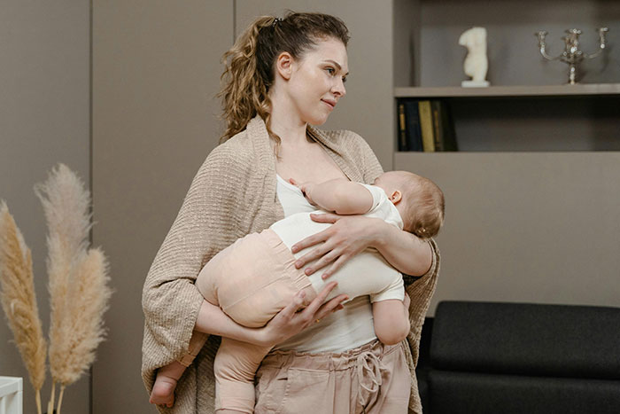 Mother breastfeeding her baby in a cozy room, illustrating key aspects of pregnancy and birth facts and experiences.