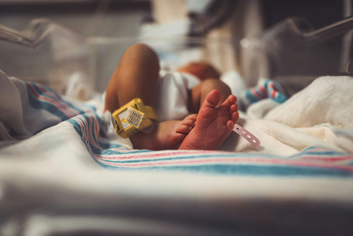 Newborn baby lying in a hospital bassinet, highlighting the realities of pregnancy and birth experiences.