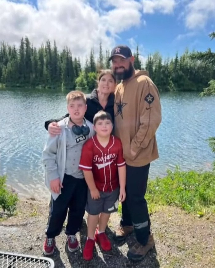 Family standing by a lake with trees behind, related to remains of missing family found after boating tragedy.