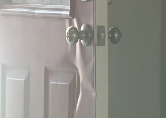 Slightly open damaged home door with dented metal near doorknobs symbolizing trauma after ICE agents raid wrong home.