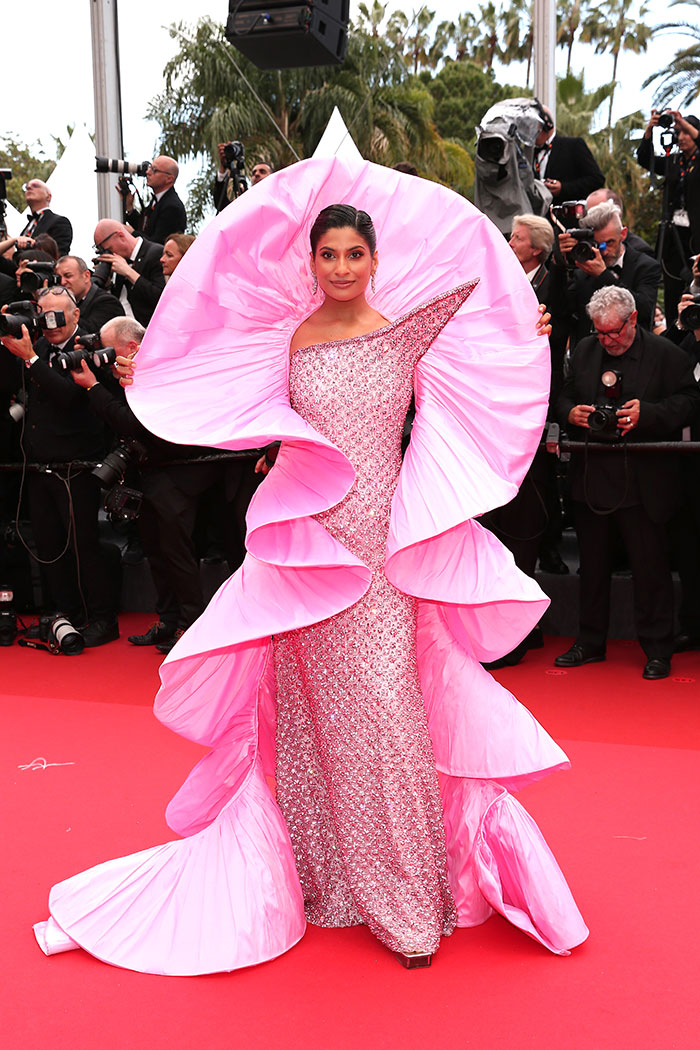 Woman in an extravagant pink ruffled gown posing on the red carpet at Cannes Film Festival fashion disaster event 2025.