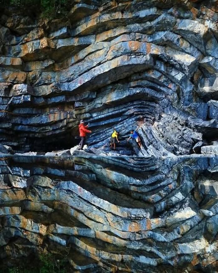 Three hikers in colorful clothing exploring towering layered rock formations showcasing nature’s breathtaking beauty.