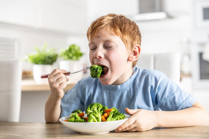 Young boy enjoying a healthy serving of broccoli and vegetables, showing strong veggie love over other meals.