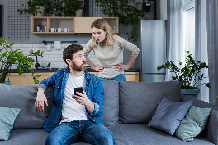 Man and woman having a tense conversation on couch, illustrating ultimatums and lost friendships from men for a woman.