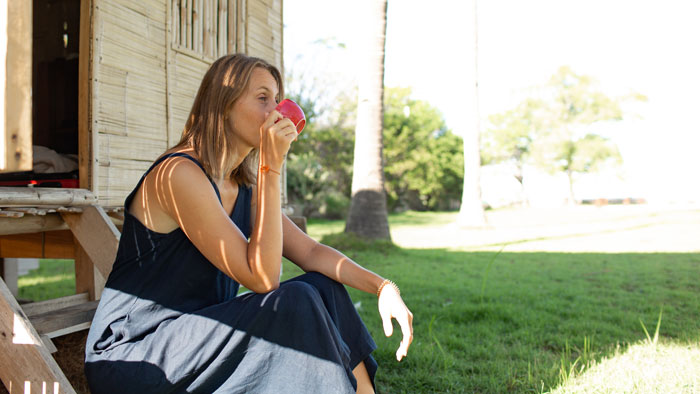 Woman sitting outside on wooden steps drinking from a red cup, related to neighbor&rsquo;s pink flamingos Facebook campaign.