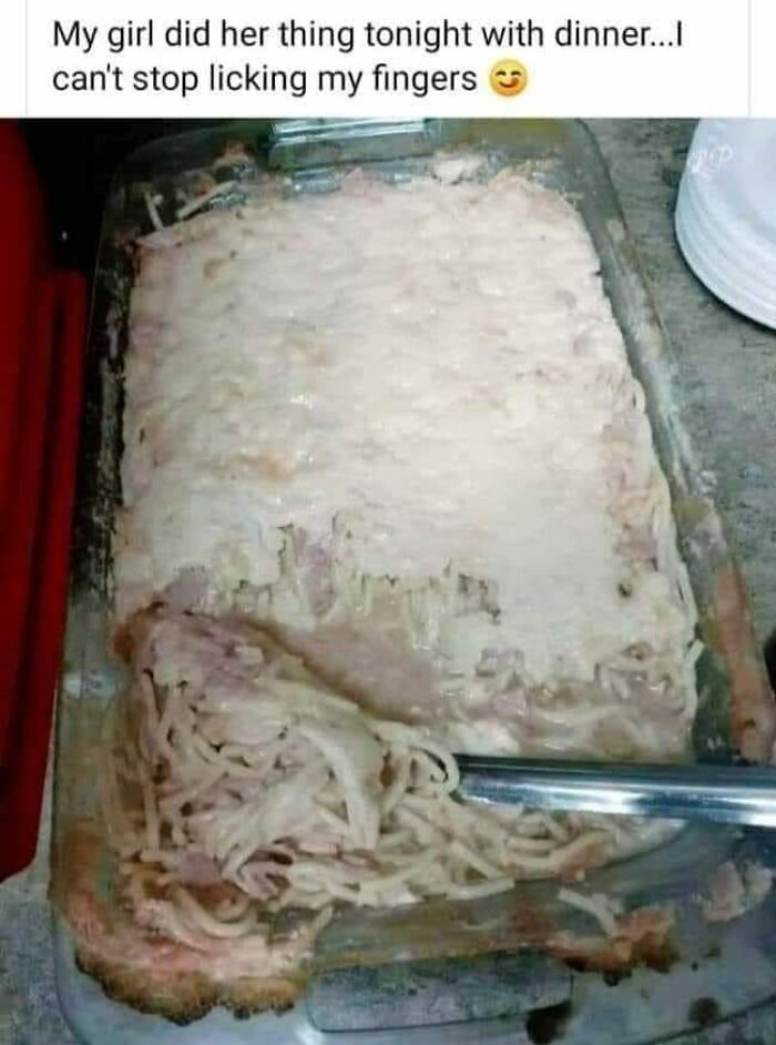 Cursed food image showing a poorly made creamy pasta dish in a glass baking tray with a serving utensil.