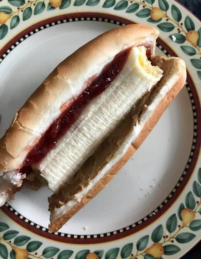 Peanut butter and jelly sandwich made with a whole banana instead of sliced bread, a cursed food pic that may trigger reactions.