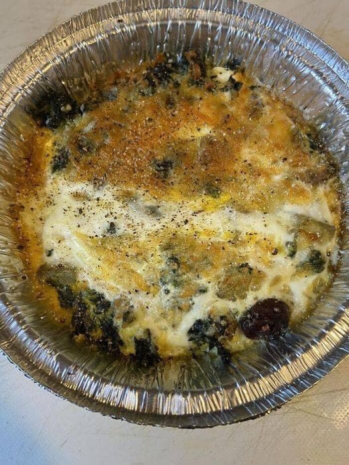Moldy and unappetizing casserole in a foil container, one of the cursed food pics that look disturbing and unappealing.