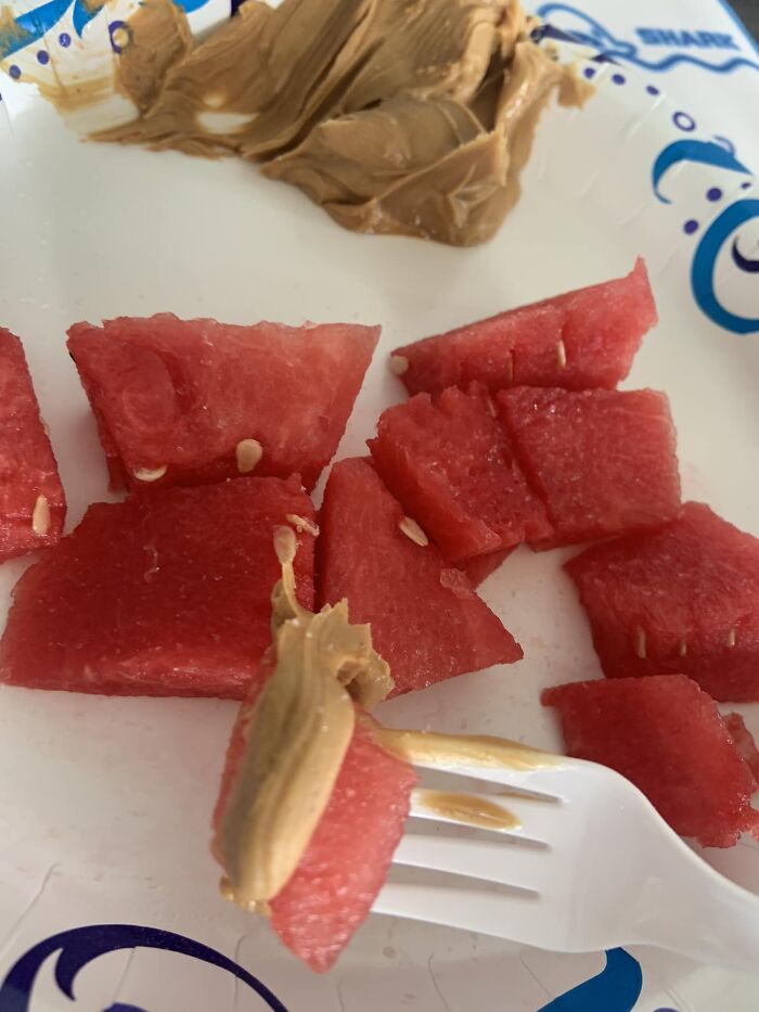 Pieces of watermelon with peanut butter on a white plate, showing a strange combination of cursed food pics.