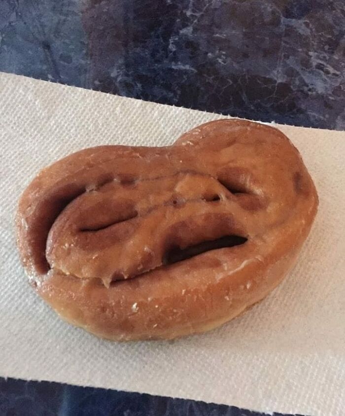 Unusual cursed food pic of a twisted pastry with a distorted face-like shape on a white napkin.