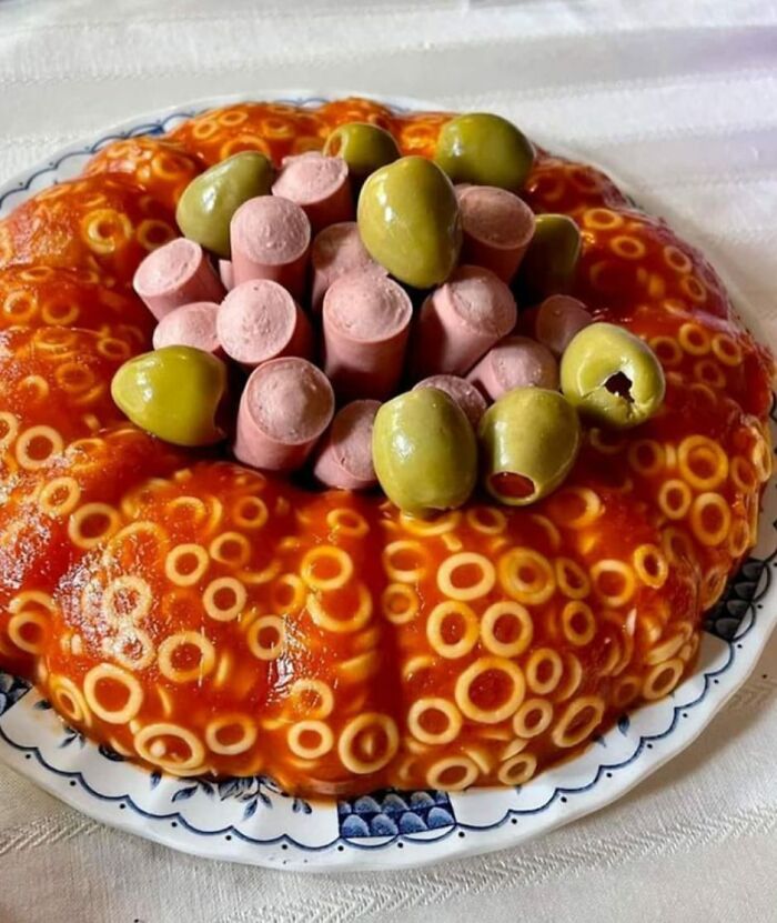 Spaghetti-O ring mold with sliced hot dogs and green olives in the center, a cursed food pic that is unsettling.