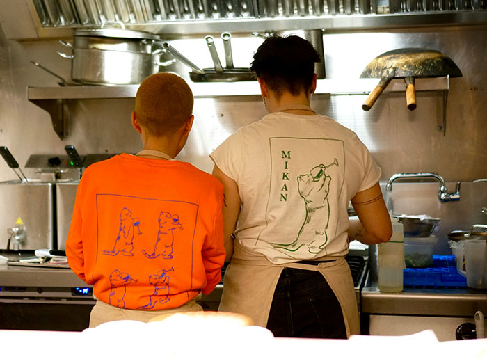 Two people cooking in a kitchen wearing graphic shirts with playful animal designs, capturing a casual and fun atmosphere.
