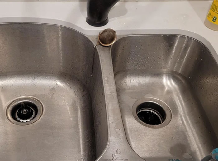 Double stainless steel kitchen sink with a black faucet and a metal pipe fixture, illustrating funny things foreigners say about the US.