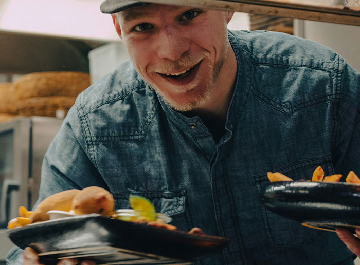 Man in a cap serving plates of food, representing Americans recalling the funniest things foreigners say about the United States.
