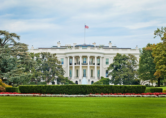 Front view of the White House with flag, representing US secret $21 trillion underground city claims by former official. Front view of the White House with flag, representing US secret $21 trillion underground city claims by former official.