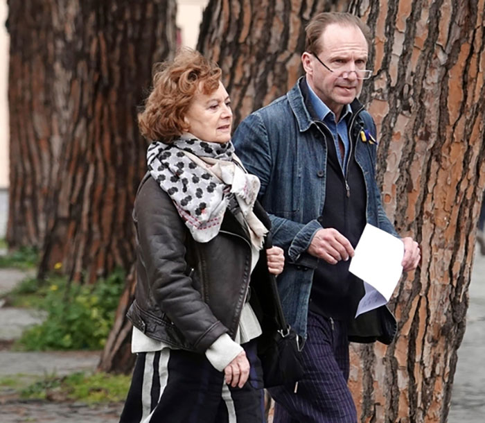 Ralph Fiennes walking outdoors with Francesca Annis, casually dressed, reuniting nearly 30 years after scandalous affair.