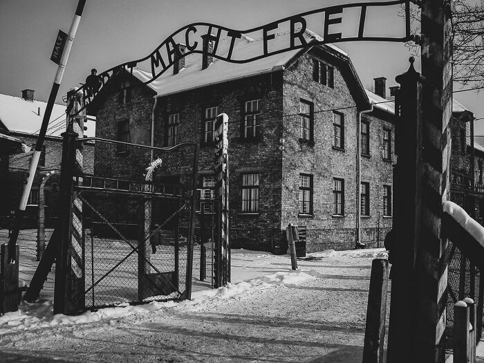 Entrance gate of Auschwitz concentration camp in black and white, evoking strong historical facts and reality questioning.