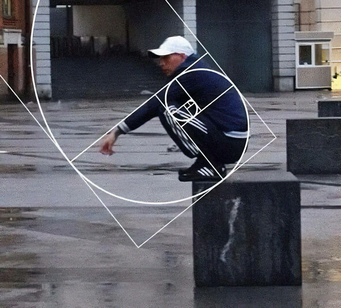 A person squatting on a concrete block in an urban area, illustrating a weird pics or it didn’t happen moment.