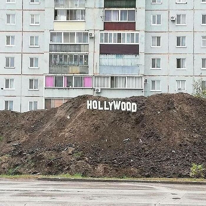 Mound of dirt with makeshift Hollywood sign placed in front of an apartment building in a weird pics or it didn’t happen moment.