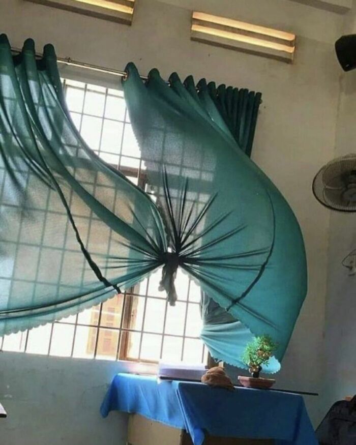 Curtains blown inward by wind, creating a weird distorted shape in a room, illustrating weird pics or it didn't happen moments.