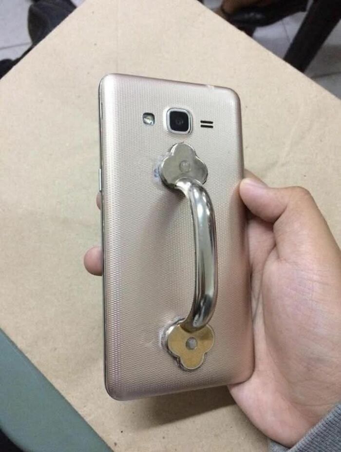 Smartphone with a metal handle attached to the back, showcasing a weird pics or it didn’t happen moment.