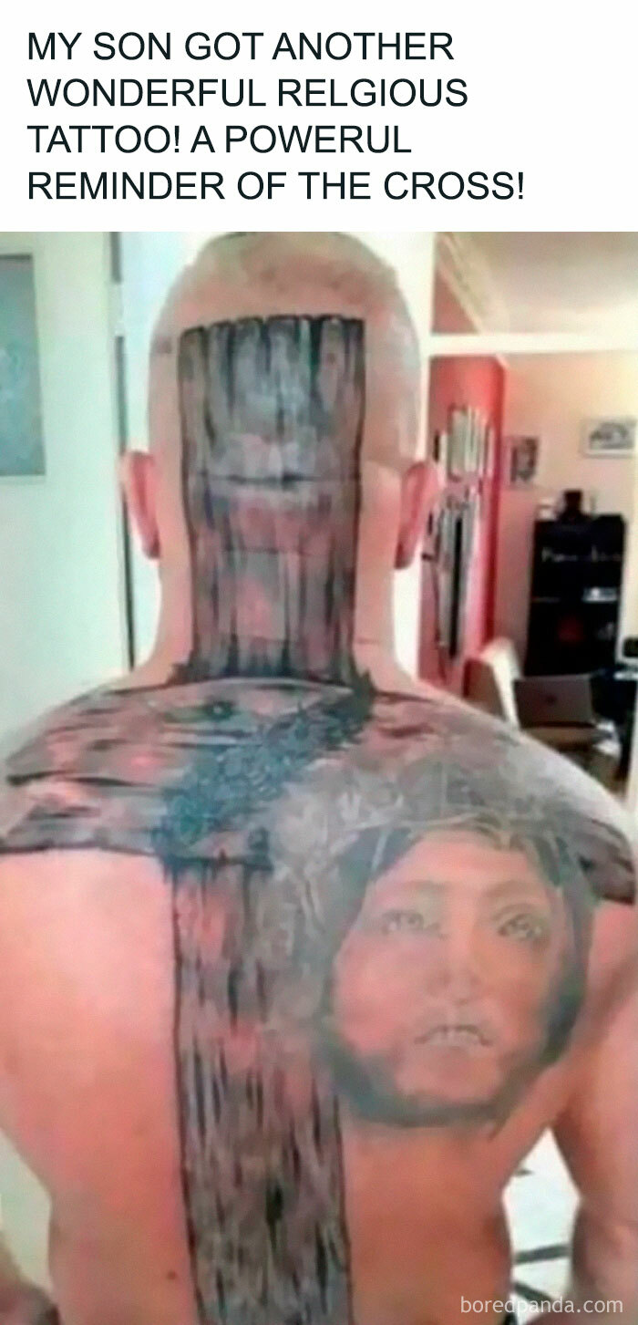 Man with funny and bad tattoos of a wooden cross and a religious face covering his back and neck indoors.