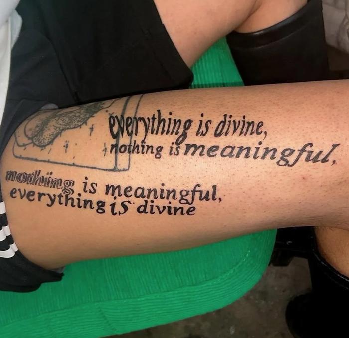 Tattoo of a confusing philosophical phrase with overlapping text on a person's upper leg showcasing funny and bad tattoos.