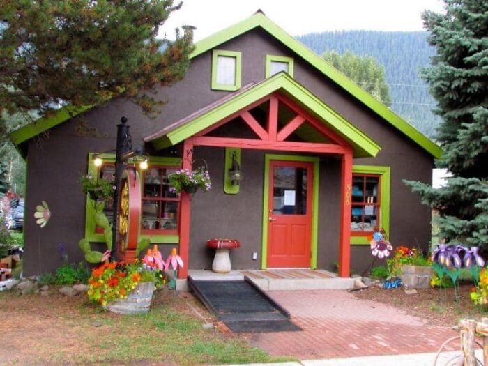 Small house with bright green trim and red door surrounded by colorful garden decorations in a real estate photo fail.