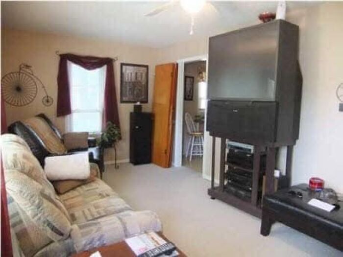 Living room with outdated large television and mismatched furniture in a worst real estate photos ever listing.