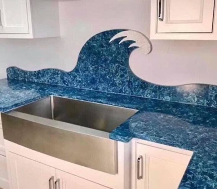 Kitchen sink with an unusual wave-shaped blue countertop and backsplash in a poorly designed real estate photo.