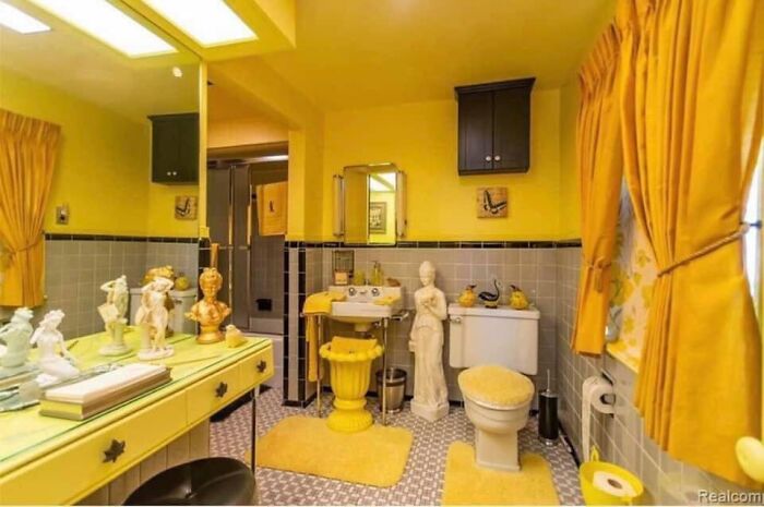 Bathroom with yellow walls, vintage decor, statues, and mismatched furnishings in worst real estate photos ever collection.